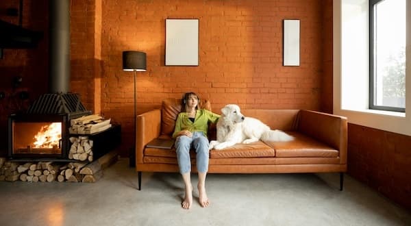 Woman relaxing on a couch with a large white dog in a loft apartment